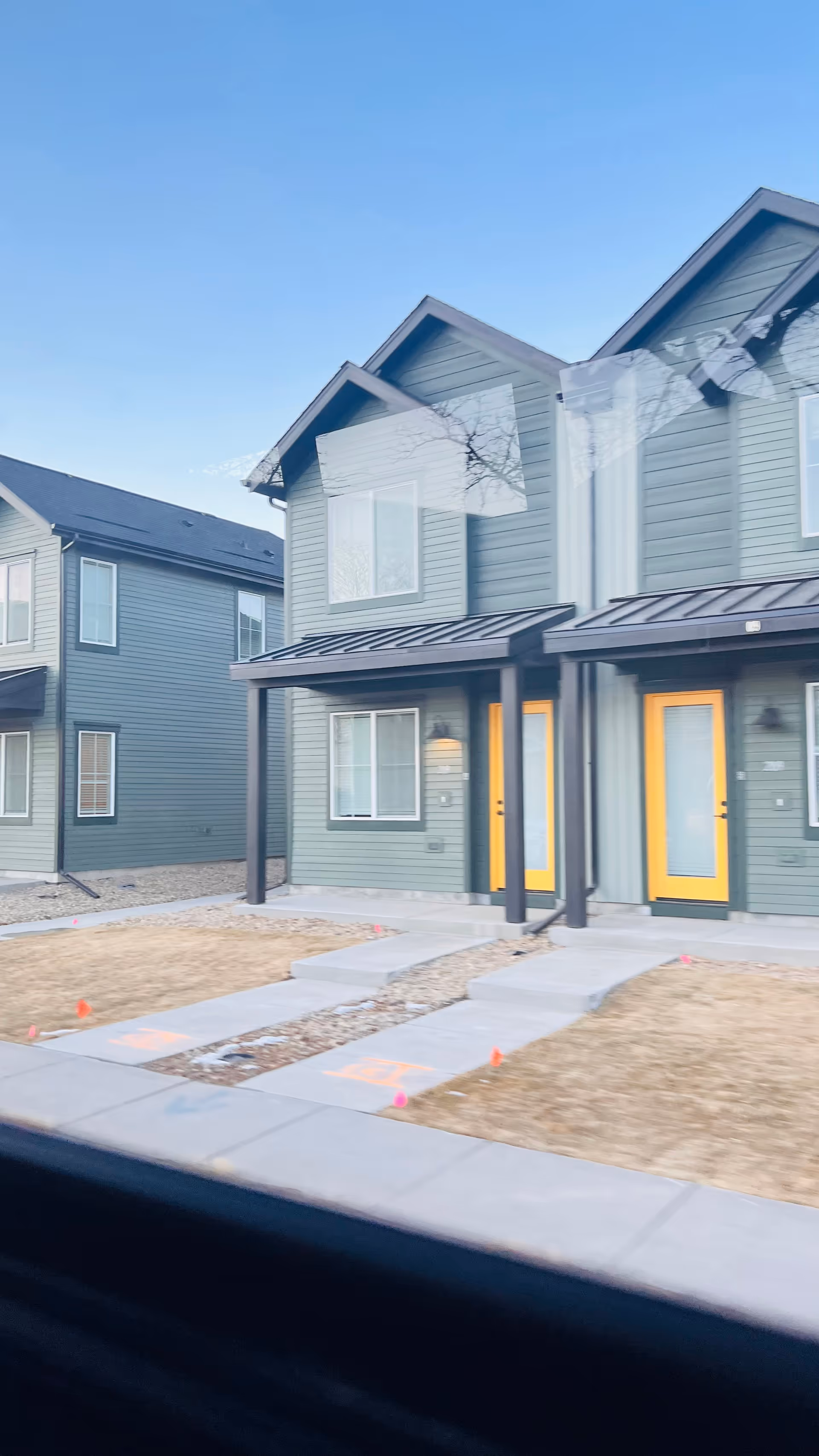 Row of green townhome-style senior living buildings with yellow doors and porches.