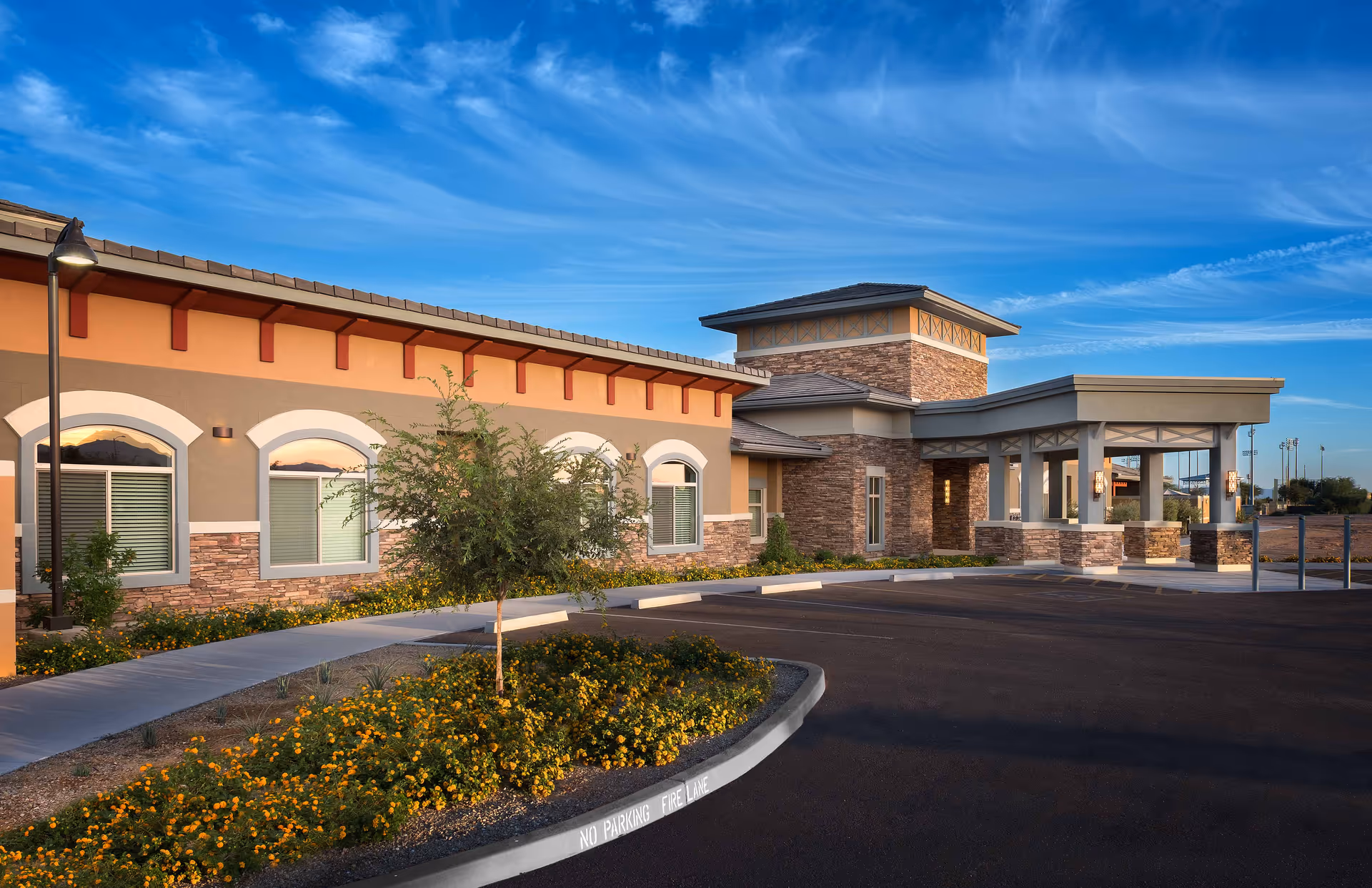 Exterior view of Mosaic Gardens Memory Care at Surprise with entrance and landscaped parking.