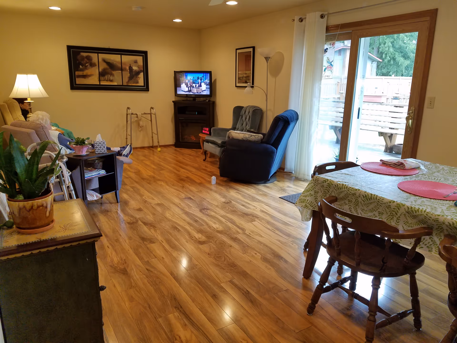 Spacious living area with recliners, sofa, TV, and dining table near sliding doors.