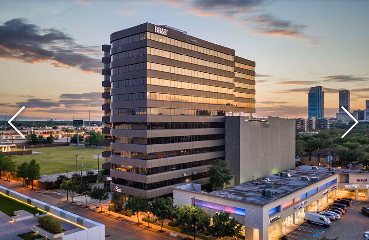 Sunset exterior view of a tall office building with surrounding parking.