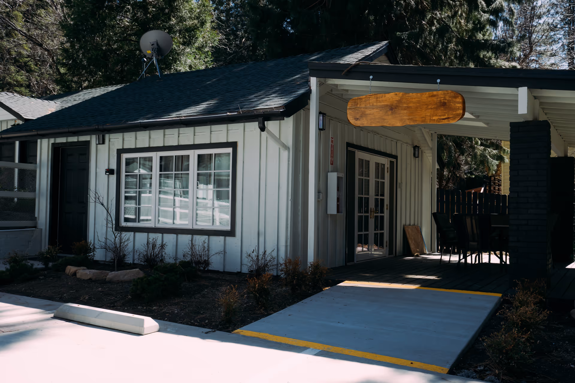 Exterior view of a senior living facility front entrance with a covered patio and seating.