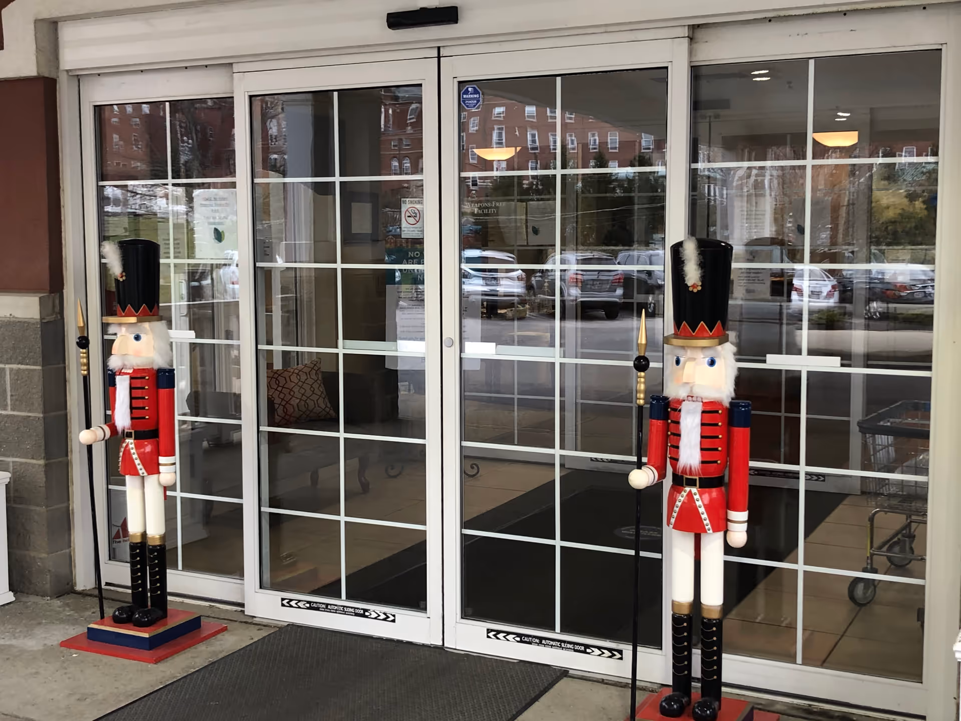 Glass double entrance doors flanked by two large decorative nutcracker soldier statues.