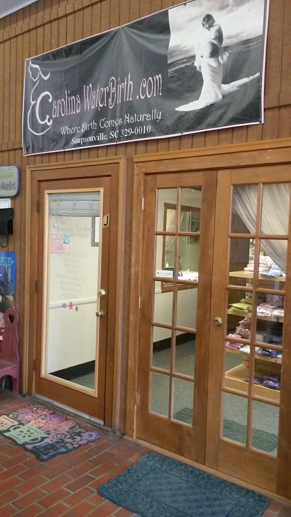 Exterior entrance with wooden French doors and banner for Carolina WaterBirth.