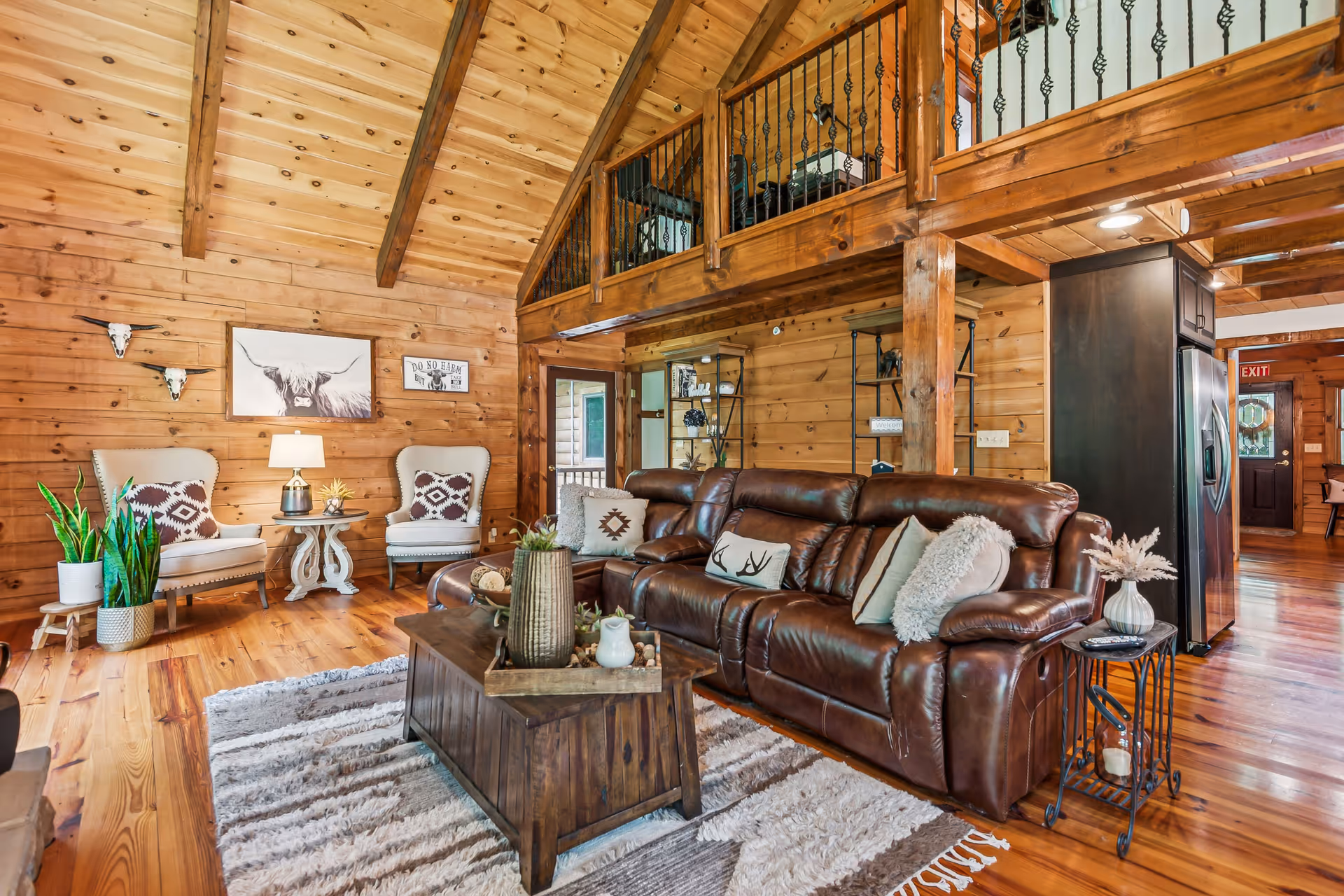 Rustic log cabin living room with leather sofa, wooden beams, and cozy seating.