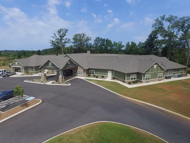 A single-story Clover Hill Senior Living building with a curved driveway and parking lot.