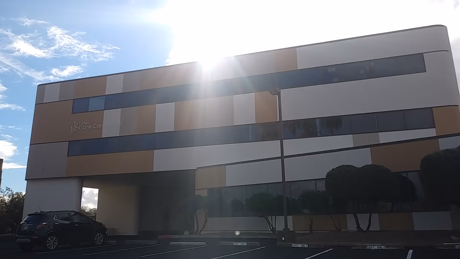 A modern, multi-colored facility exterior labeled 'Total Care Connections' under a sunny sky.