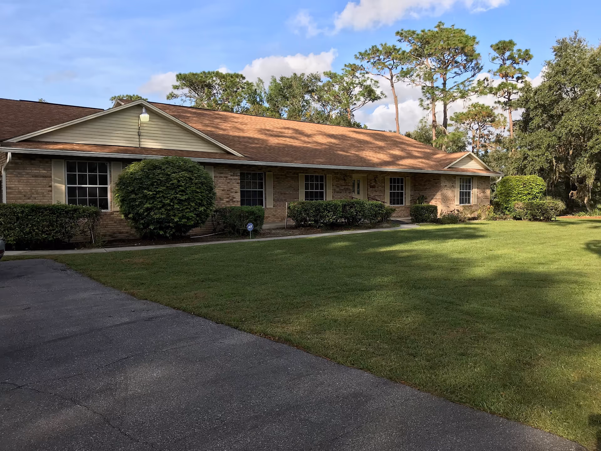 Front view of a single-story brick facility with manicured lawn and tall trees.