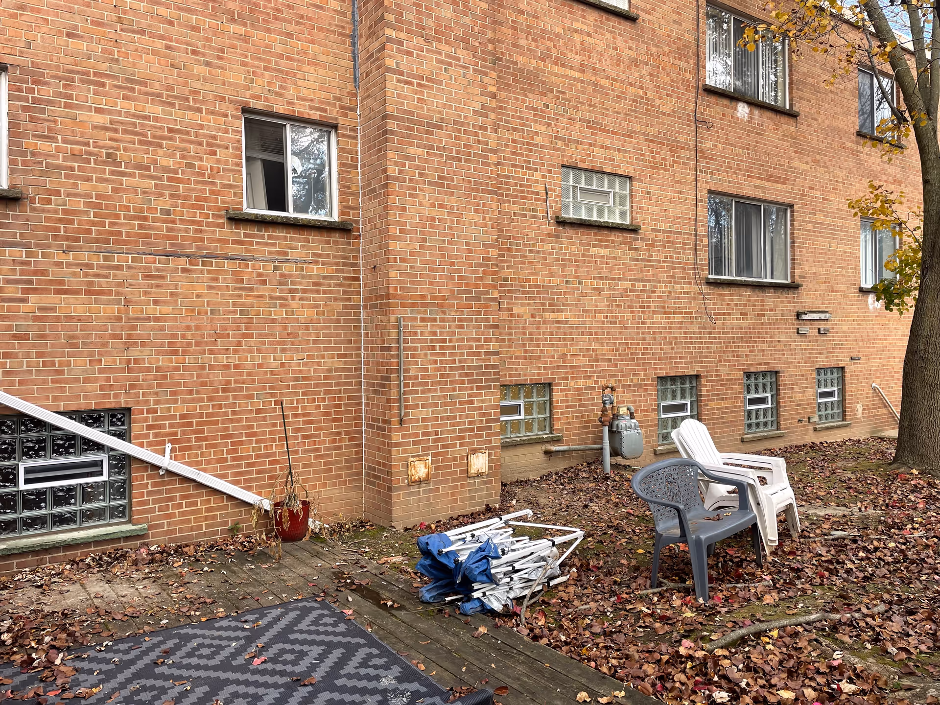 Exterior view of a brick senior living building with scattered outdoor chairs.