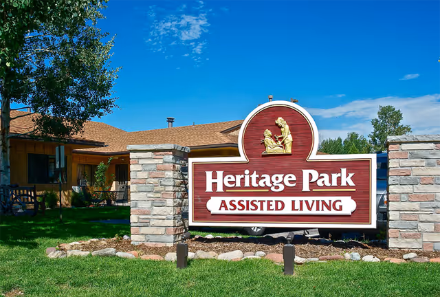 Outdoor signage for Heritage Park Assisted Living with brick pillars and a building behind.
