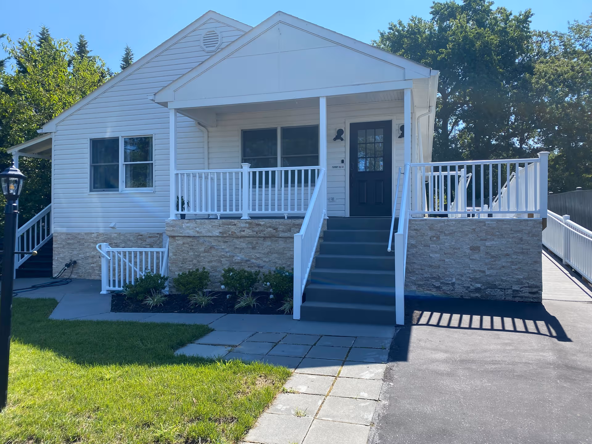 White single-story building with front porch, stairs, and stone veneer on facade.