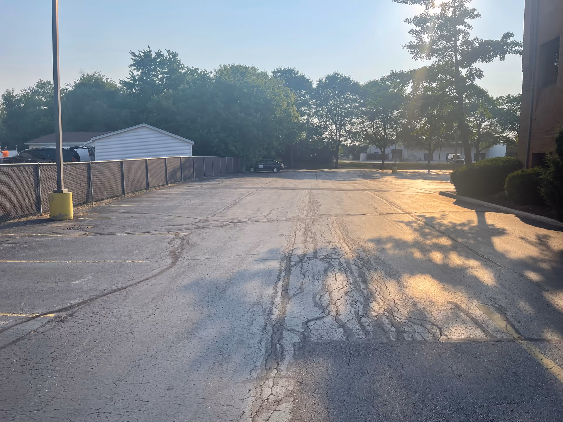 Outdoor parking lot of a senior care facility, empty, with fence and trees.