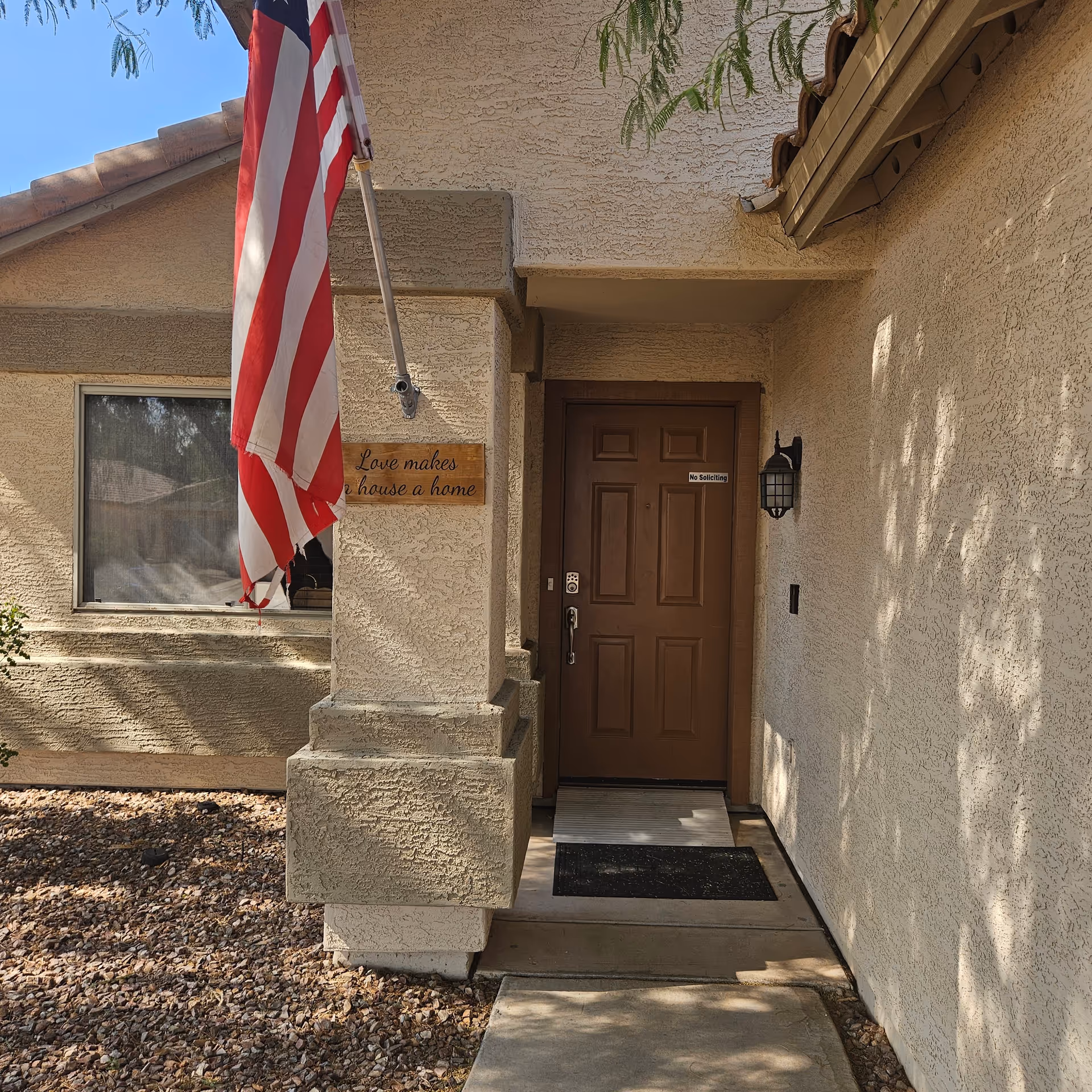 Entrance of a beige stucco senior living facility with an American flag.