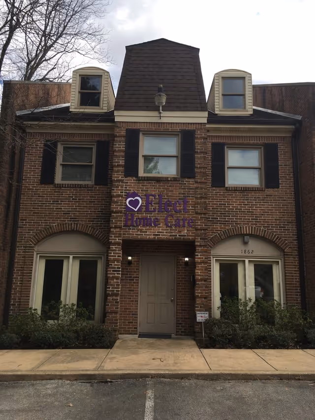 Brick building front with Elect Home Care sign, arched windows, and sidewalk entrance.