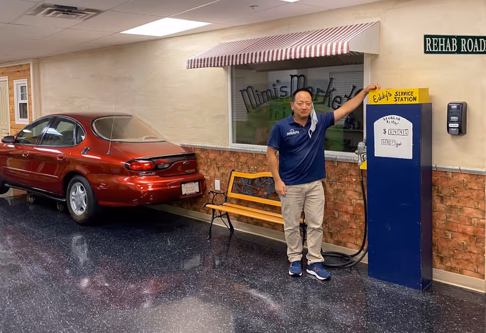 Man in blue polo stands beside a vintage gas pump inside facility.