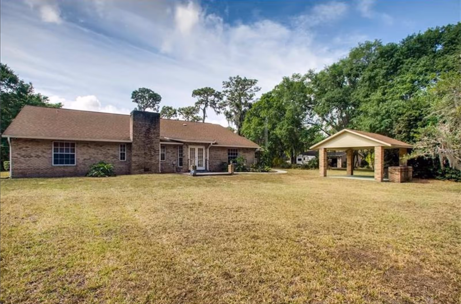 Single-story brick senior living facility with a grassy yard and a wooden pavilion.