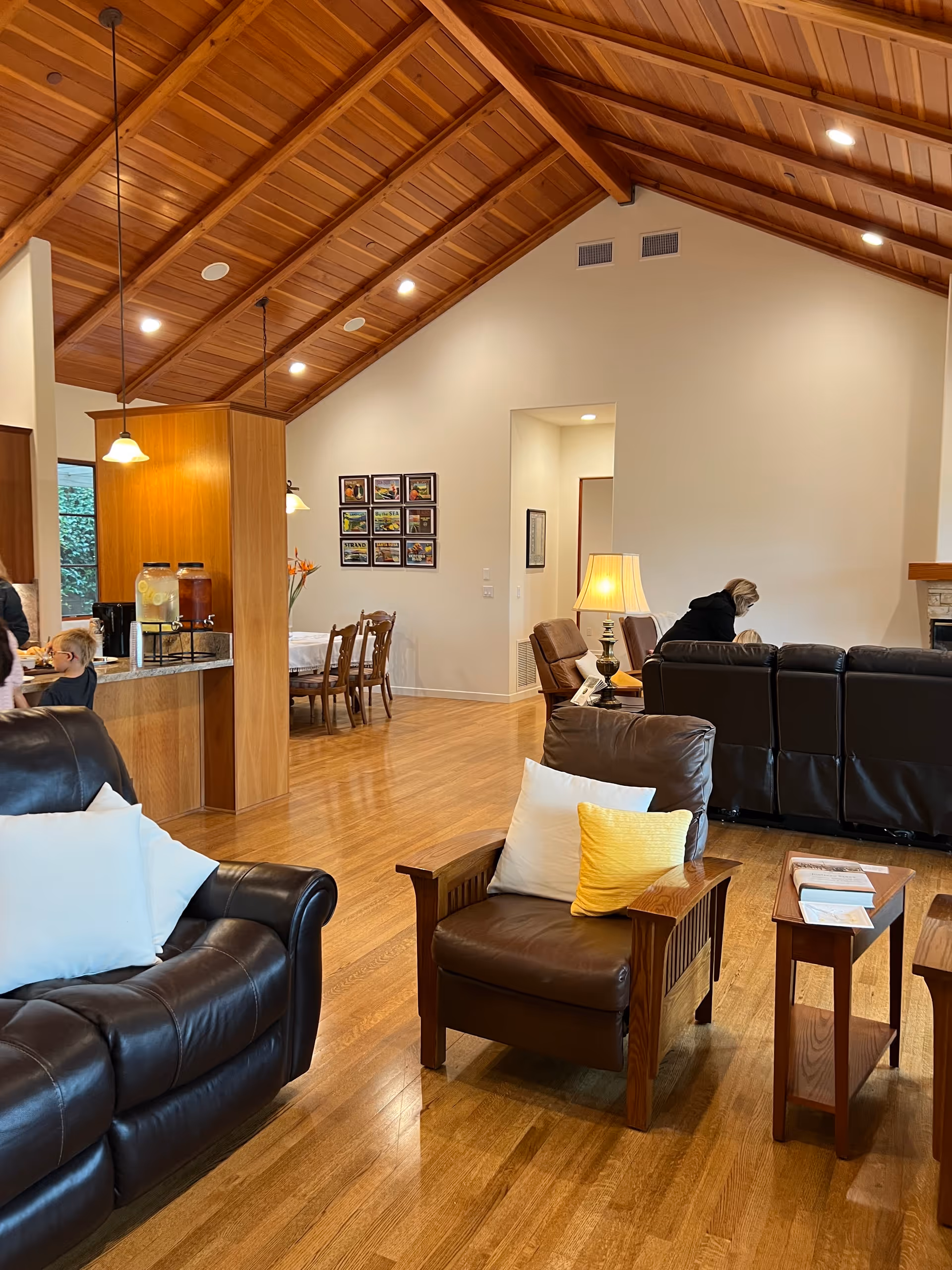 Spacious senior living lounge with leather seating, wood floors, and a high wooden ceiling.