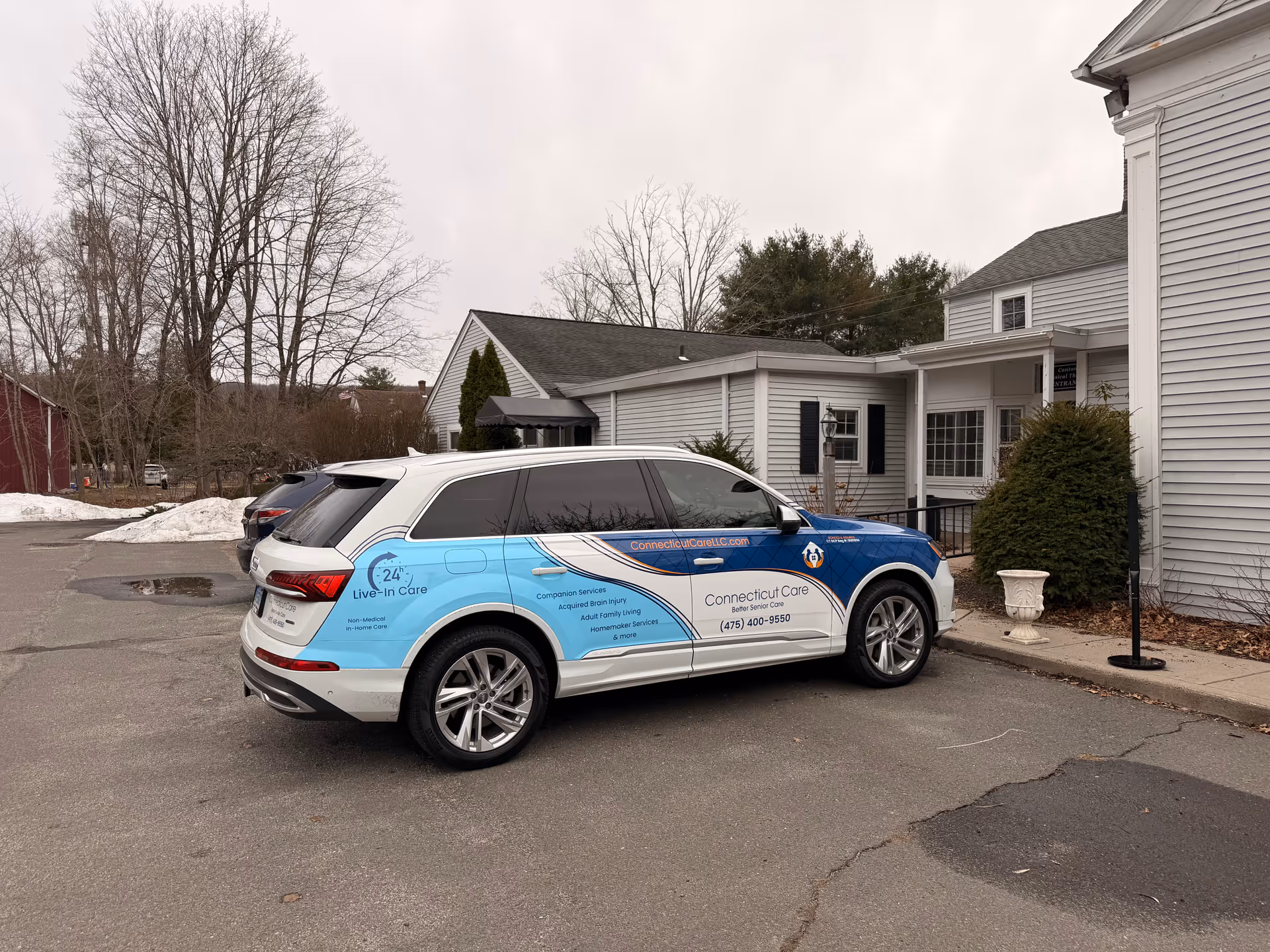 Branded Connecticut Care vehicle parked in front of a gray senior facility building.