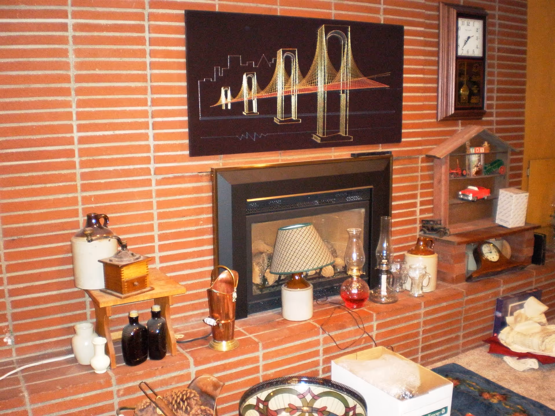 Brick fireplace with mantle, clock, shelving, and assorted decor in a cozy living room.