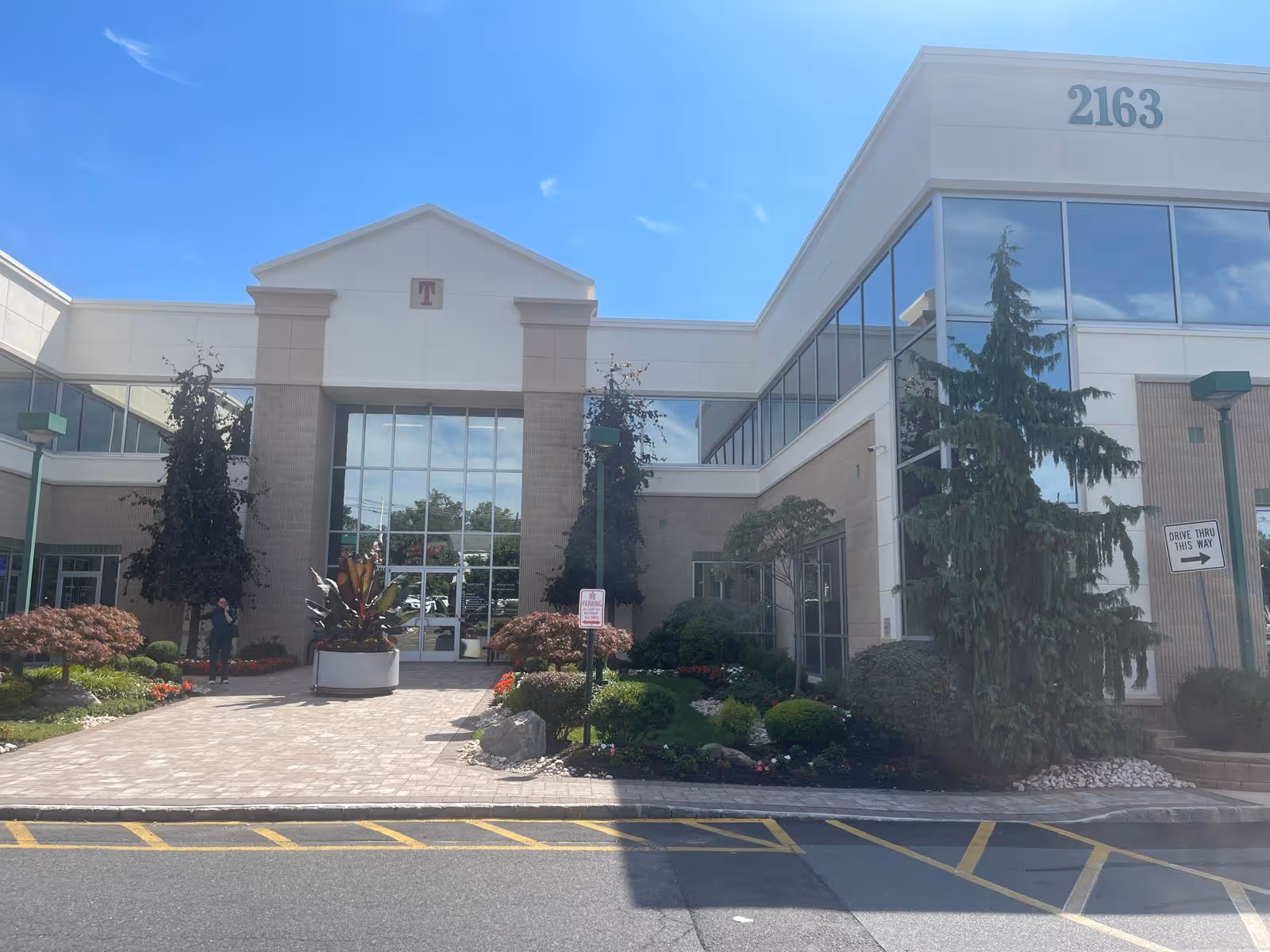Exterior view of a modern senior care facility entrance with glass doors and landscaping.