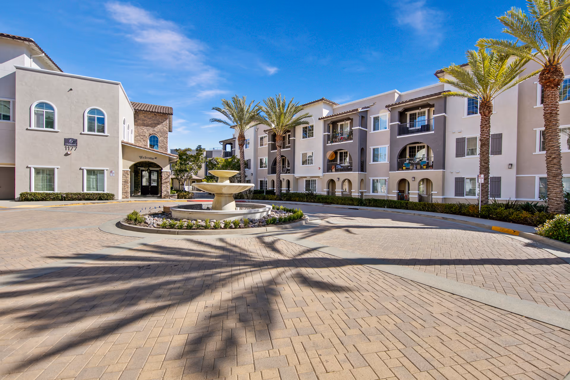 Courtyard entrance of Meridian at Lake San Marcos with a central fountain and palm trees.
