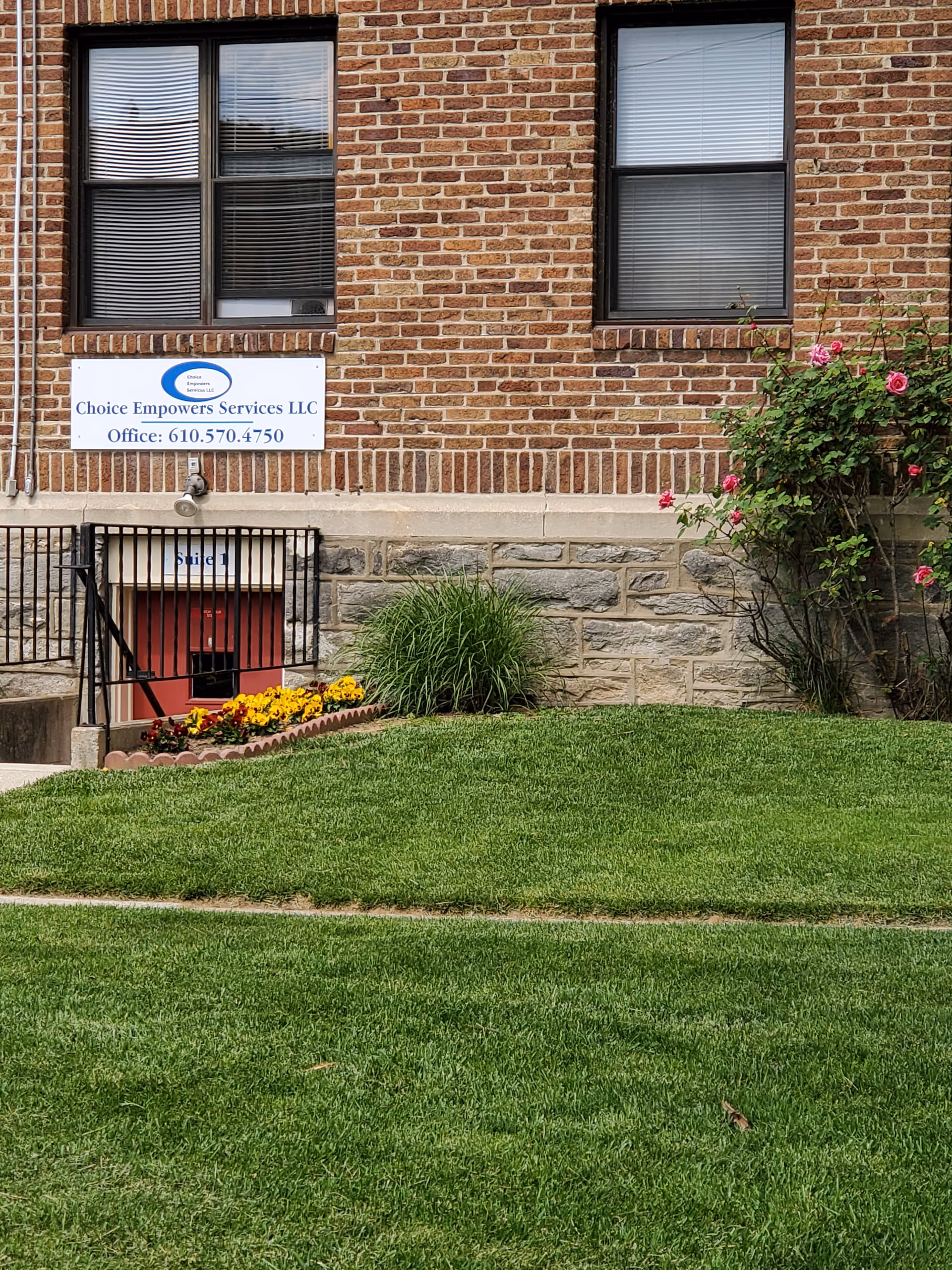 Brick building exterior with a Choice Empowers Services LLC sign and landscaped lawn.