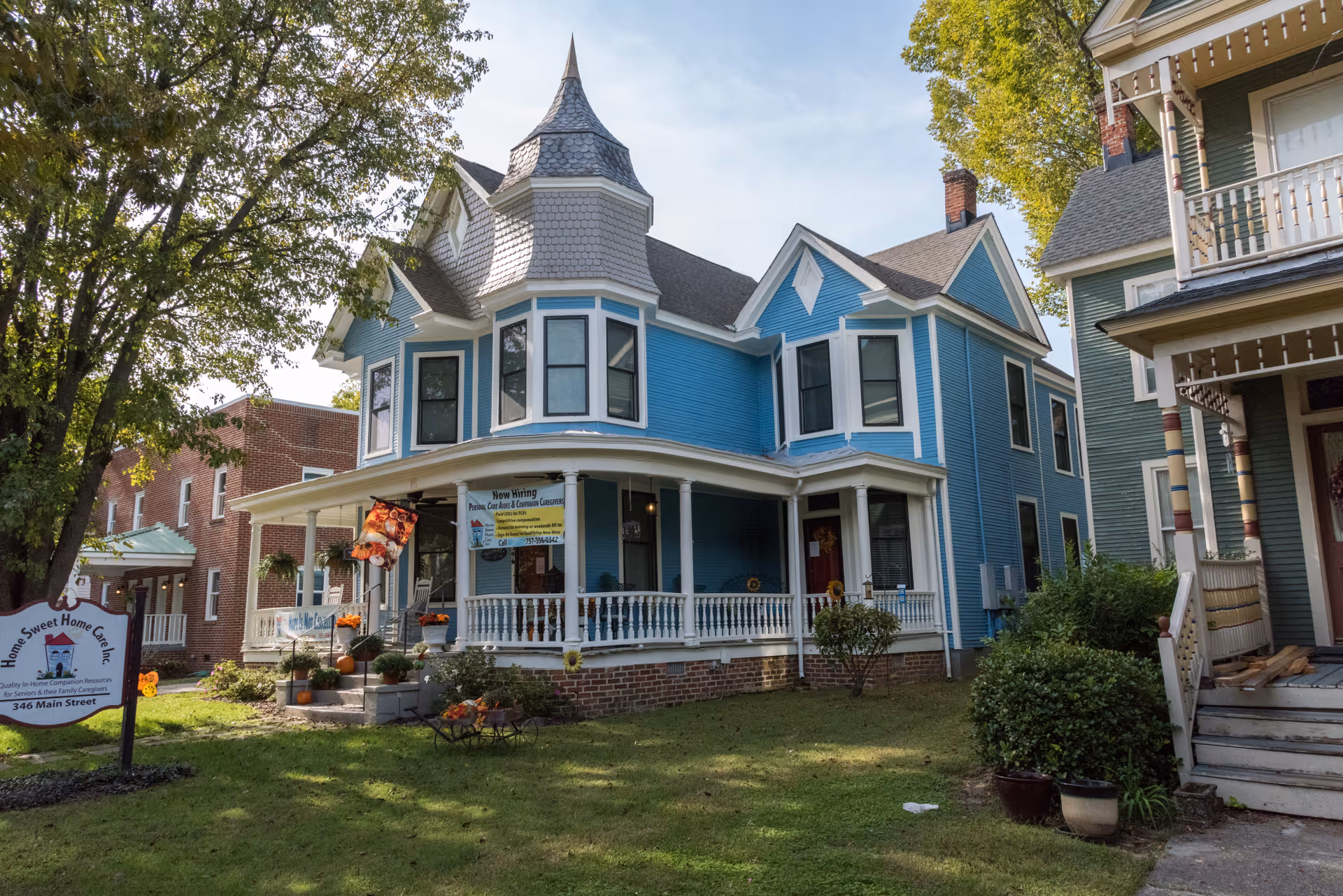 Blue Victorian-style senior care home with wraparound porch and surrounding greenery.