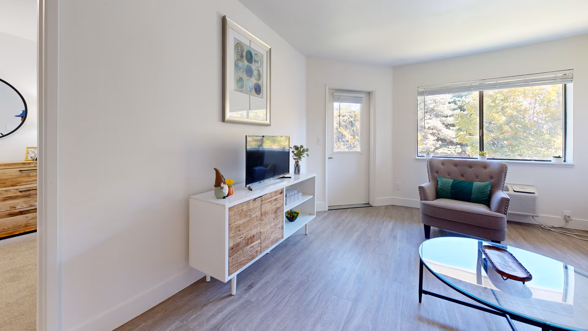 Bright senior living living room with armchair, TV, coffee table, and large windows.