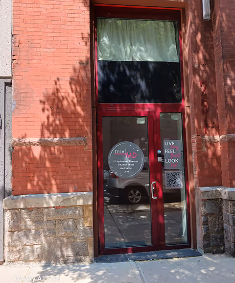 Red-framed glass door entrance on brick building with modMD signage