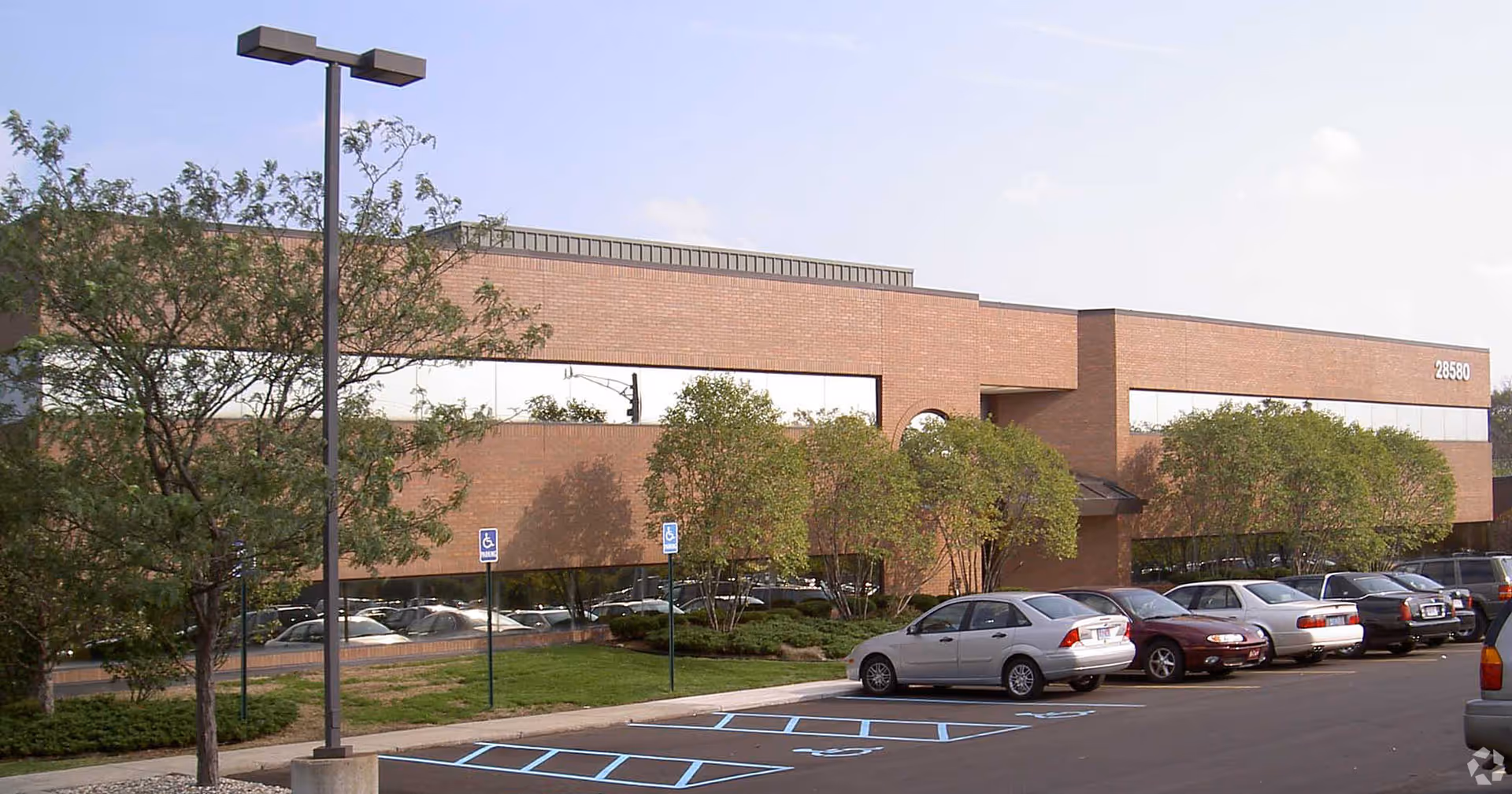 Bloom Homecare facility exterior with parking lot, trees, and blue sky.