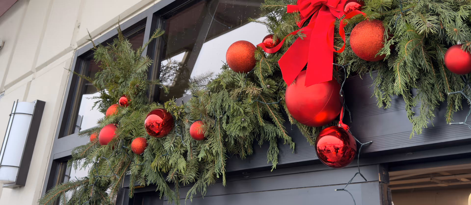 Holiday garland with red ornaments decorates the building's exterior doorway.