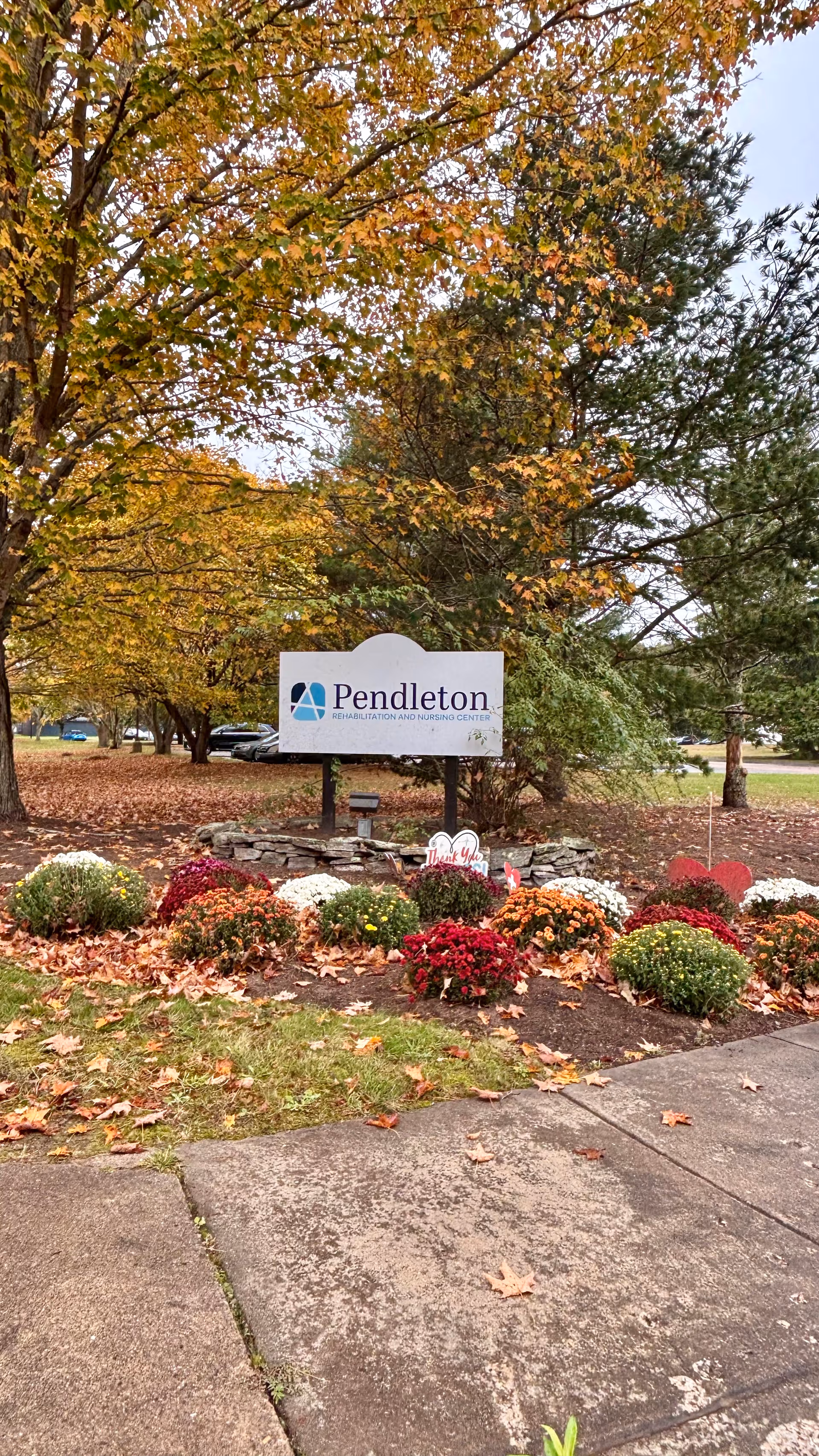 Fall foliage and flowers frame the Pendleton Health & Rehabilitation Center sign.