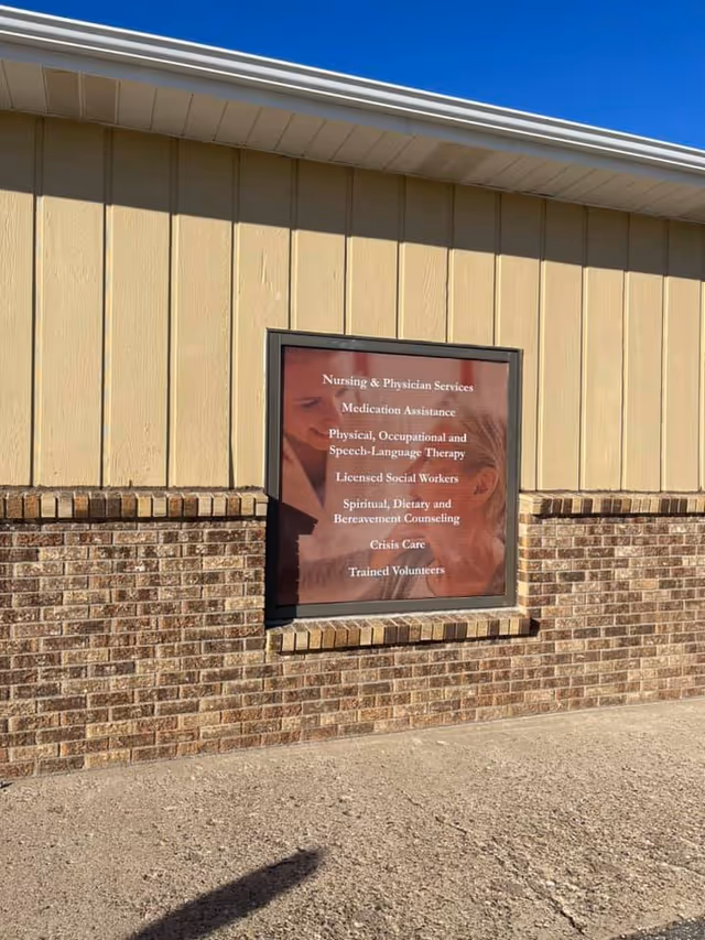 Beige exterior wall with a framed window sign listing nursing and support services.