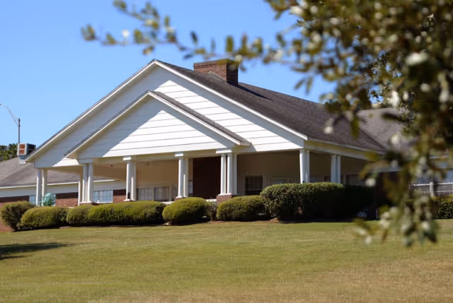 Exterior view of Hillcrest senior living building with a covered front porch and shrubs.
