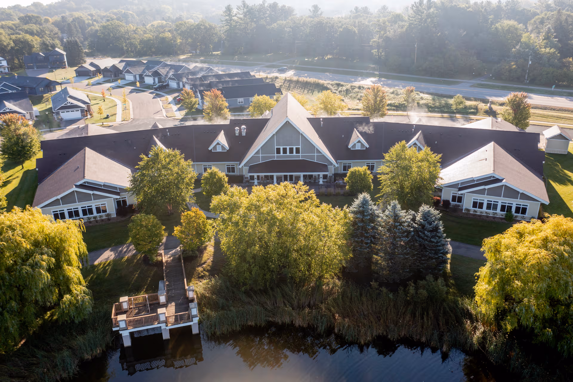 Aerial view of Comforts of Home River Falls campus with lakefront and trees.