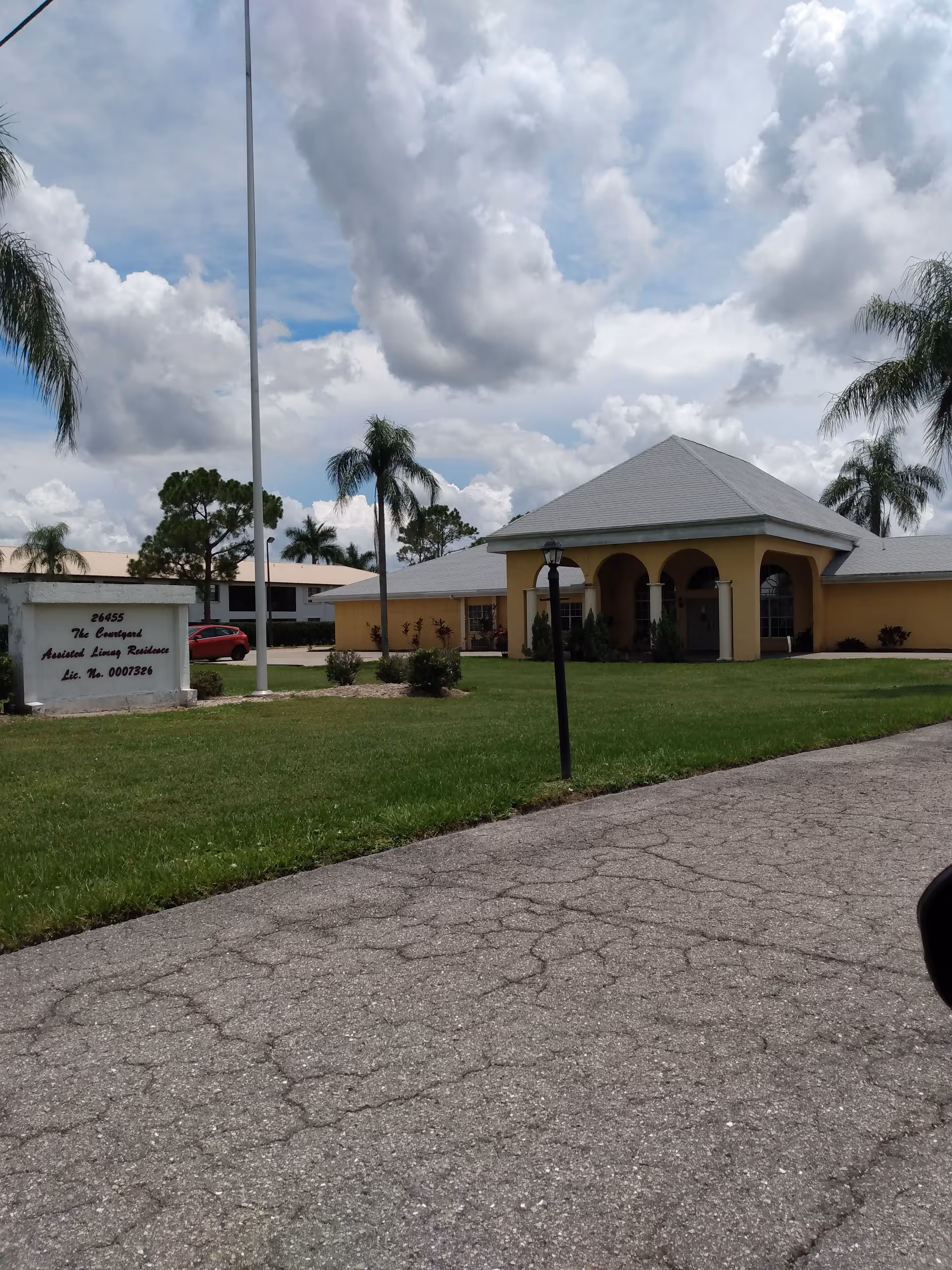 Exterior view of Courtyard Retirement Center with yellow arches, lawn, and driveway