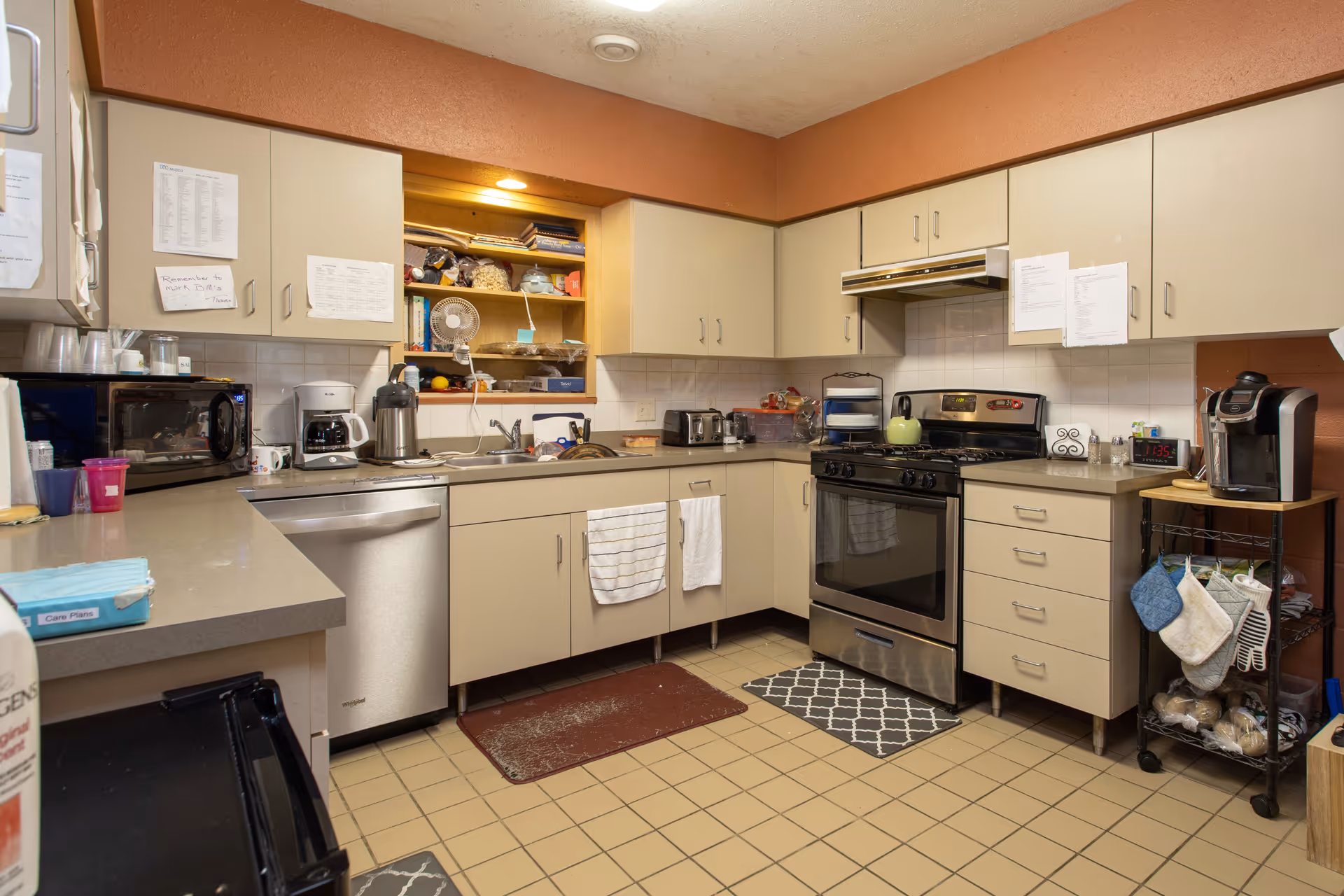 Compact kitchen in a senior living facility with stove, sink, and appliances.