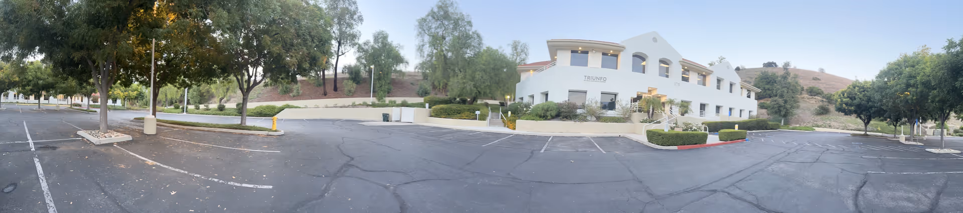 Wide exterior view of BrightStar Care facility with parking lot, trees, and white building.