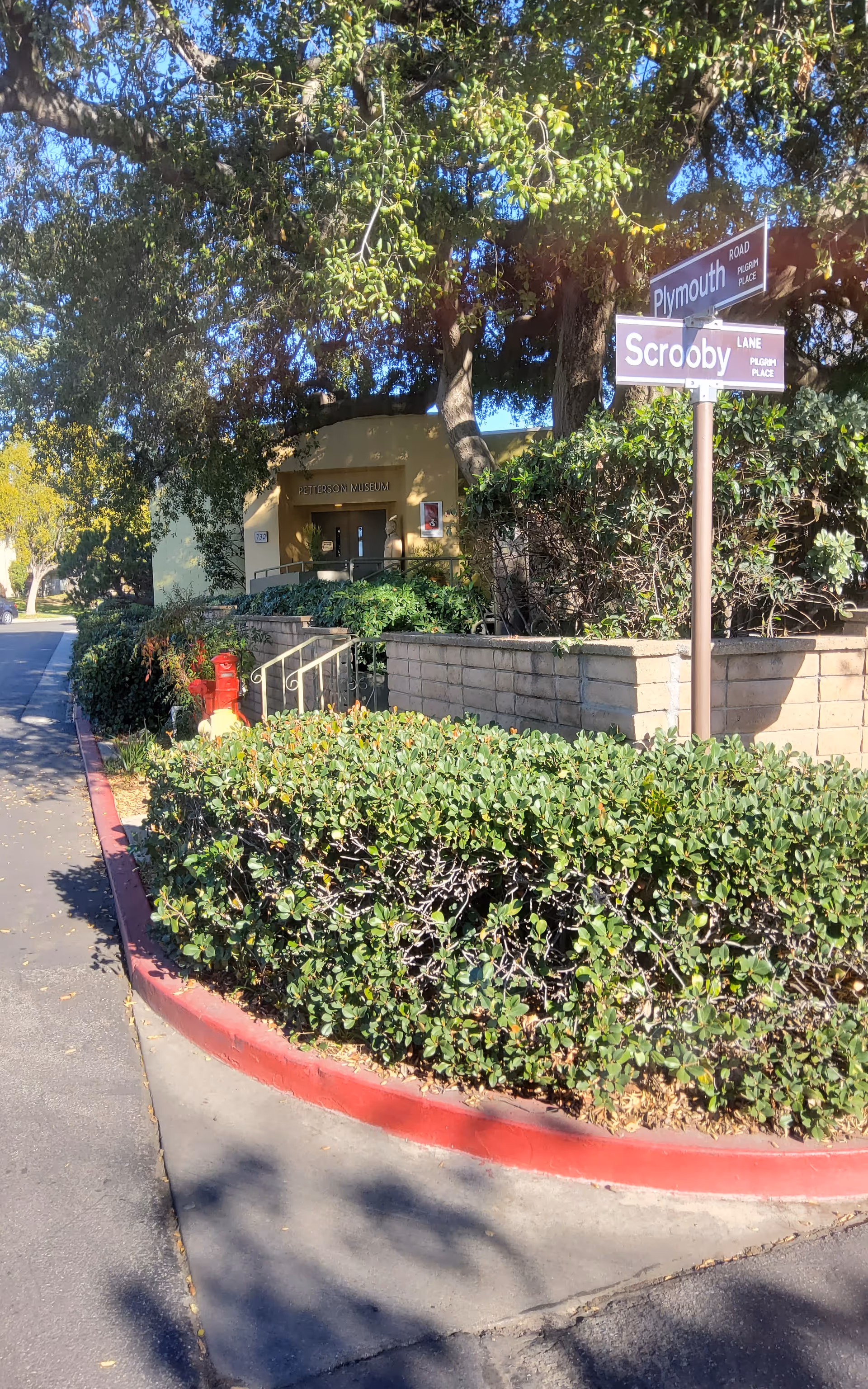 Exterior view of Pilgrim Place Health Services Center entrance with signs and greenery.