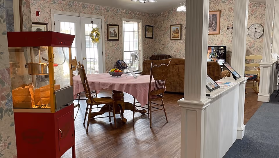 Cozy interior dining area with a round table, pink tablecloth, and chairs.