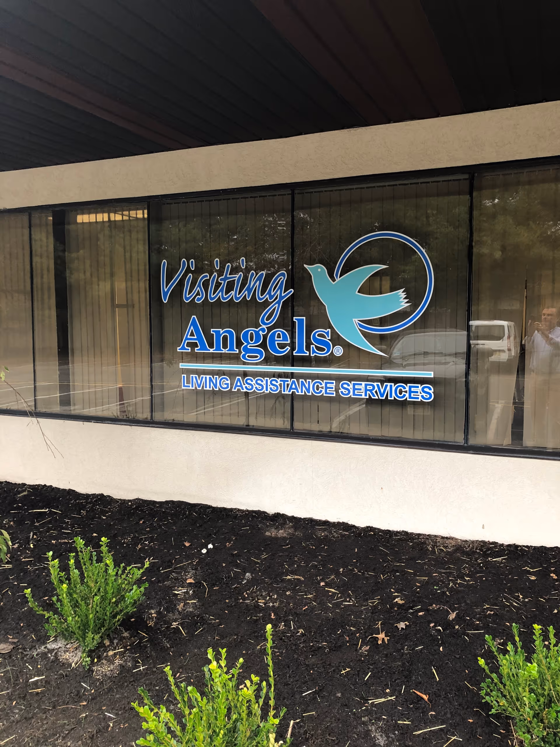 Front exterior of Visiting Angels building with large blue signage on windows.