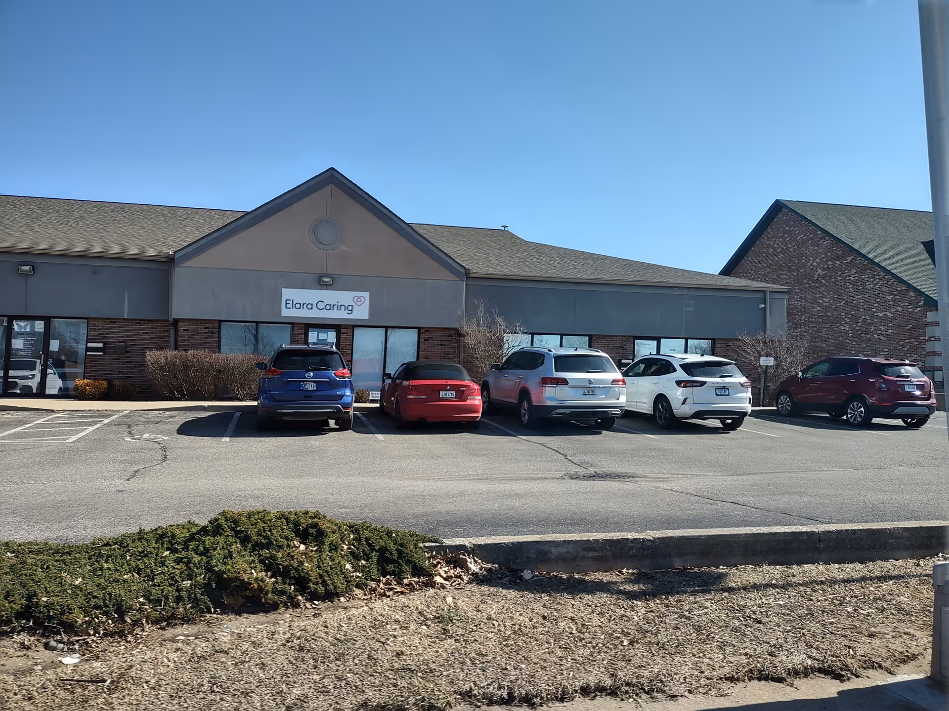 Exterior view of Elara Caring facility with parked cars.