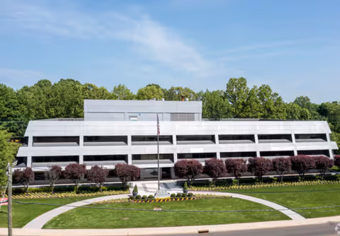 Exterior view of a modern multi-level medical facility with manicured lawn and flags.