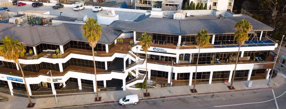 Aerial view of a two-story building exterior with palm trees along the street.