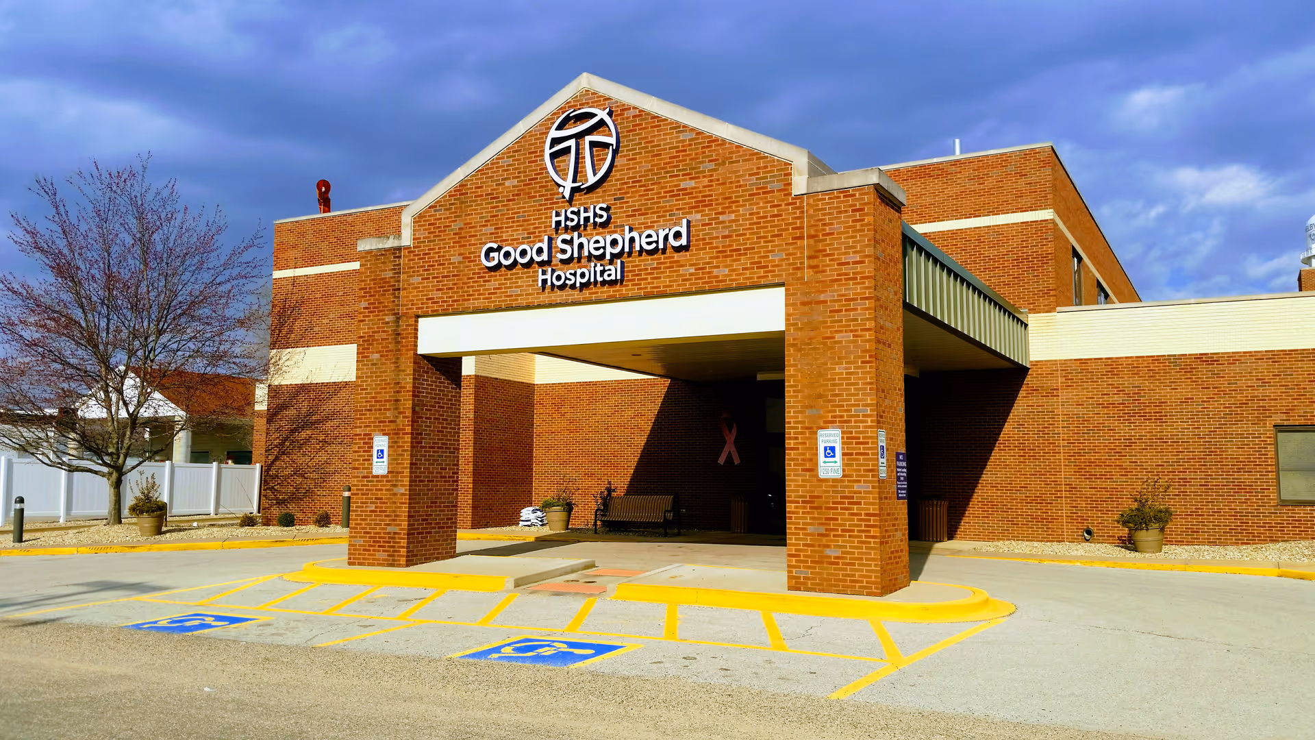 Brick hospital front with entrance canopy, HSHS Good Shepherd Hospital sign, and handicap parking.