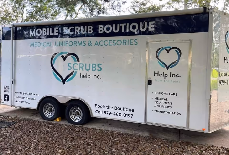 White mobile trailer labeled 'Mobile Scrub Boutique' with Help Inc. branding and logo.