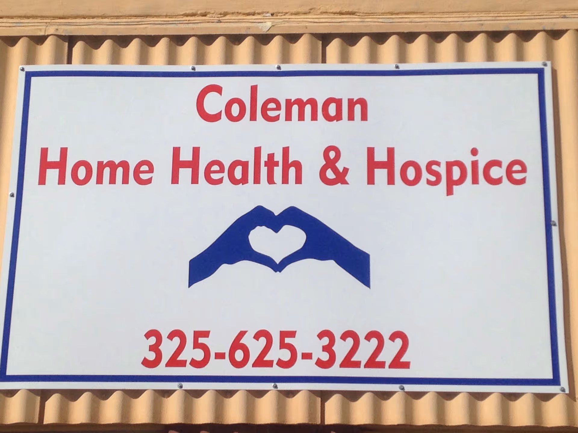 A large Coleman Home Health & Hospice sign with blue heart logo on beige siding.