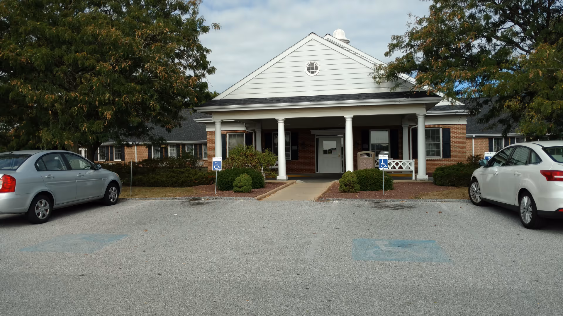 Front view of York North senior living facility entrance with pillars and parked cars.