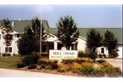 Exterior view of Mill Pond senior living facility with landscaped entrance and sign.
