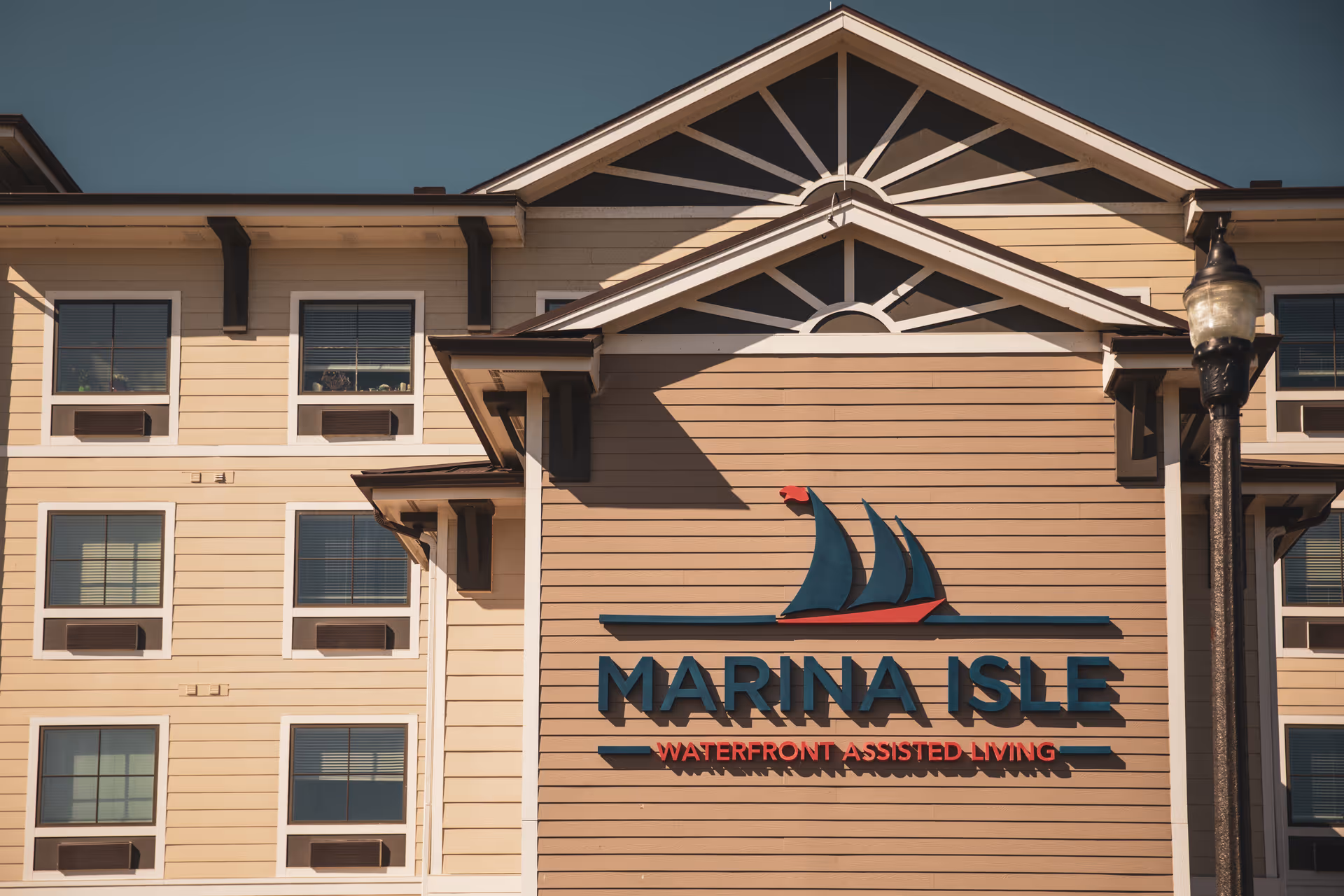 Facade of Marina Isle Waterfront Assisted Living with a large sailboat logo and prominent signage.
