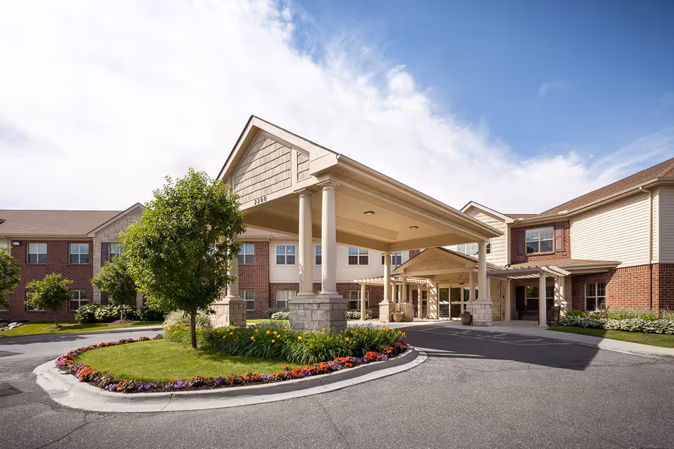 Entrance to a senior living building with a circular garden and covered driveway.